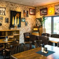 Mit Bildern dekorierte Wände in einem Restaurant mit edlen Holztischen