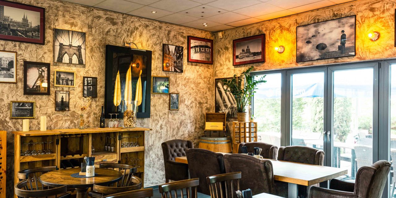 Mit Bildern dekorierte Wände in einem Restaurant mit edlen Holztischen